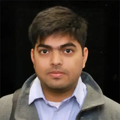 A headshot of Akhil Nayabu standing in front of a black background.