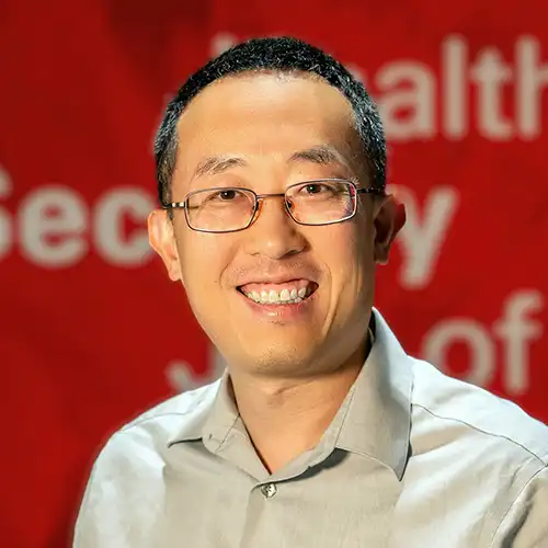 A headshot of Renran Tian standing in front of a red background.