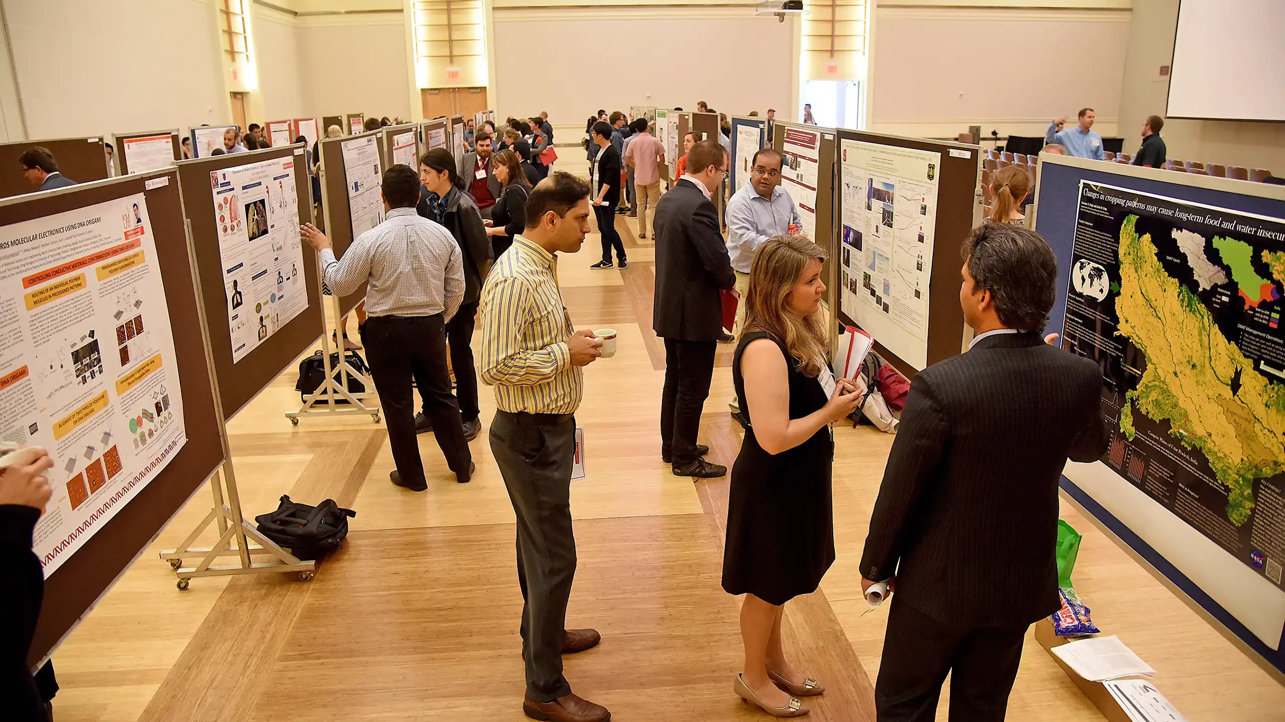 Publications displayed at a conference. Posters are set up in rows for views to walk through and talk about the projects.