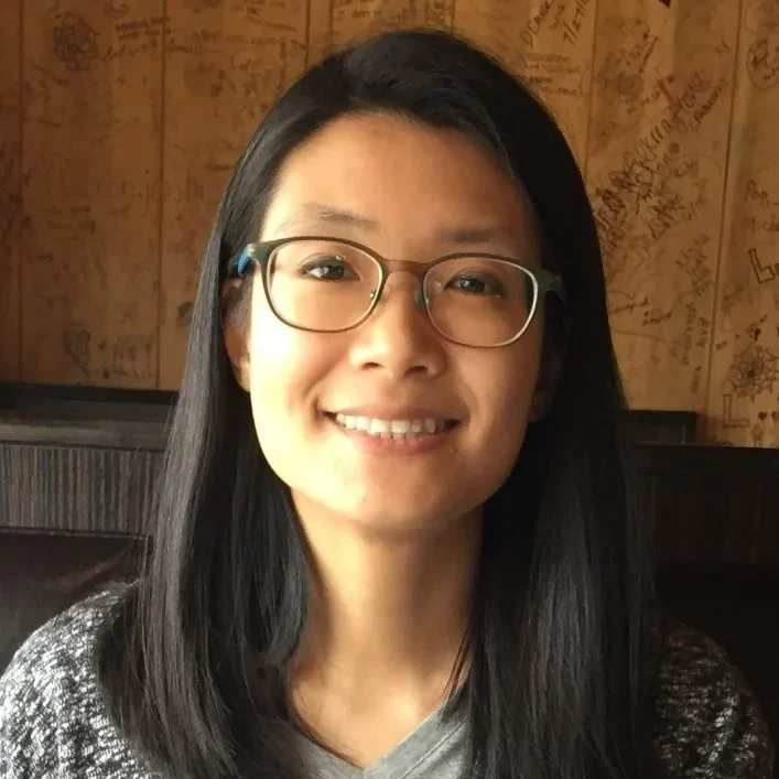 A headshot of Karen Chen standing in front of a wooden wall.