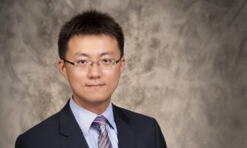 A headshot of Ziteng Wang standing in front of a grayish-brown marbled background.