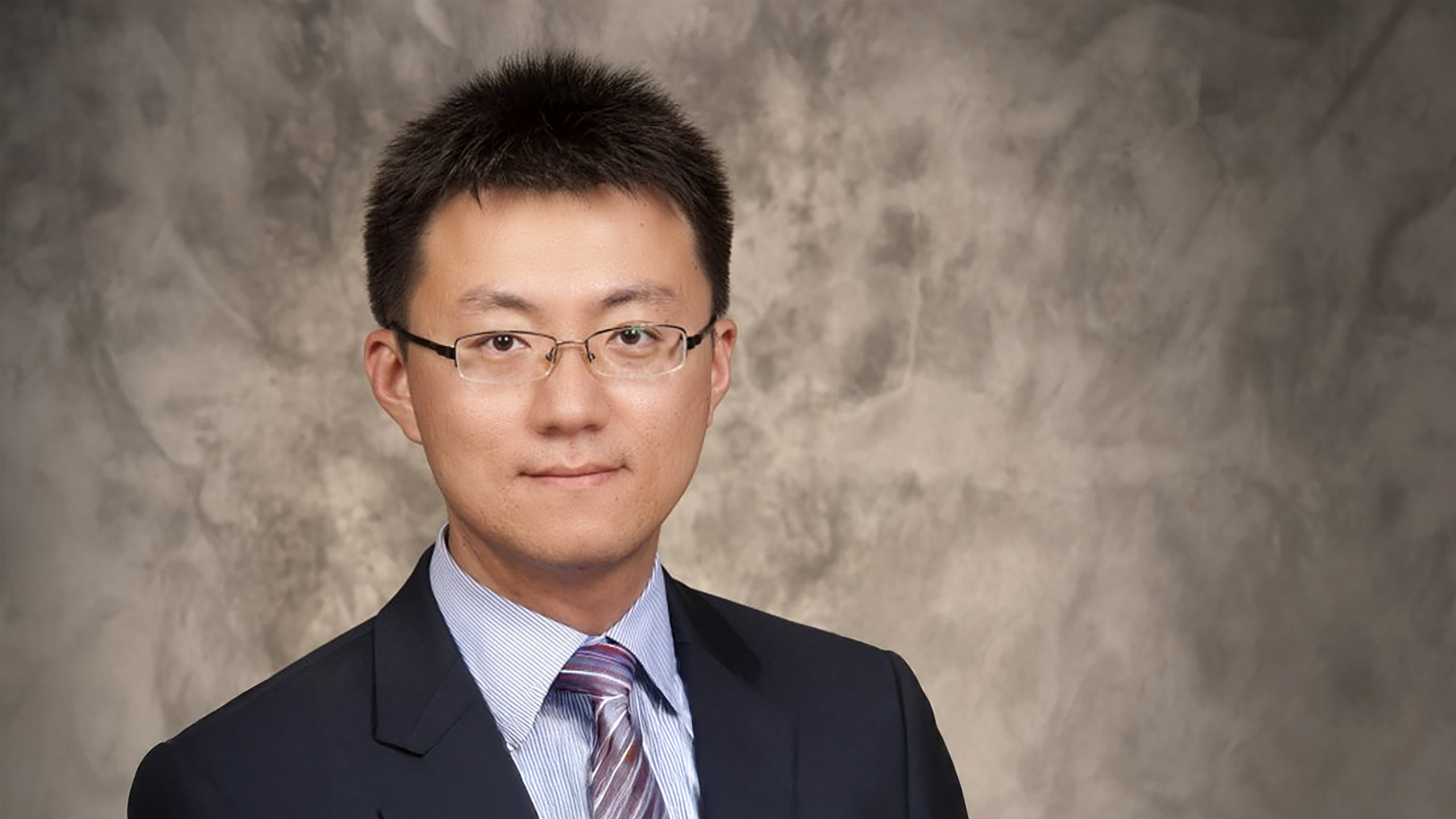 A headshot of Ziteng Wang standing in front of a grayish-brown marbled background.