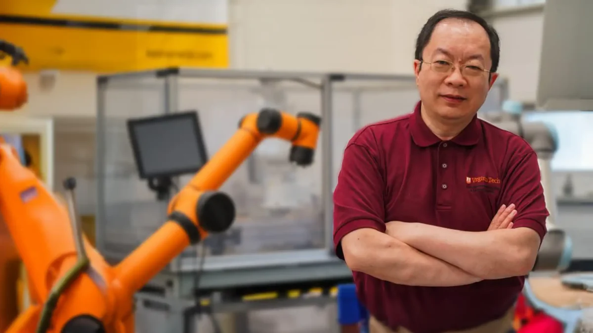 Zhenyu Kong working in a lab with a orange robot.