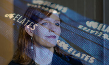 A headshot of Julie Swann covered by an extremely transparent image of the words ELATES.