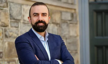 A headshot of Salt Tunc standing in front of an old stone building