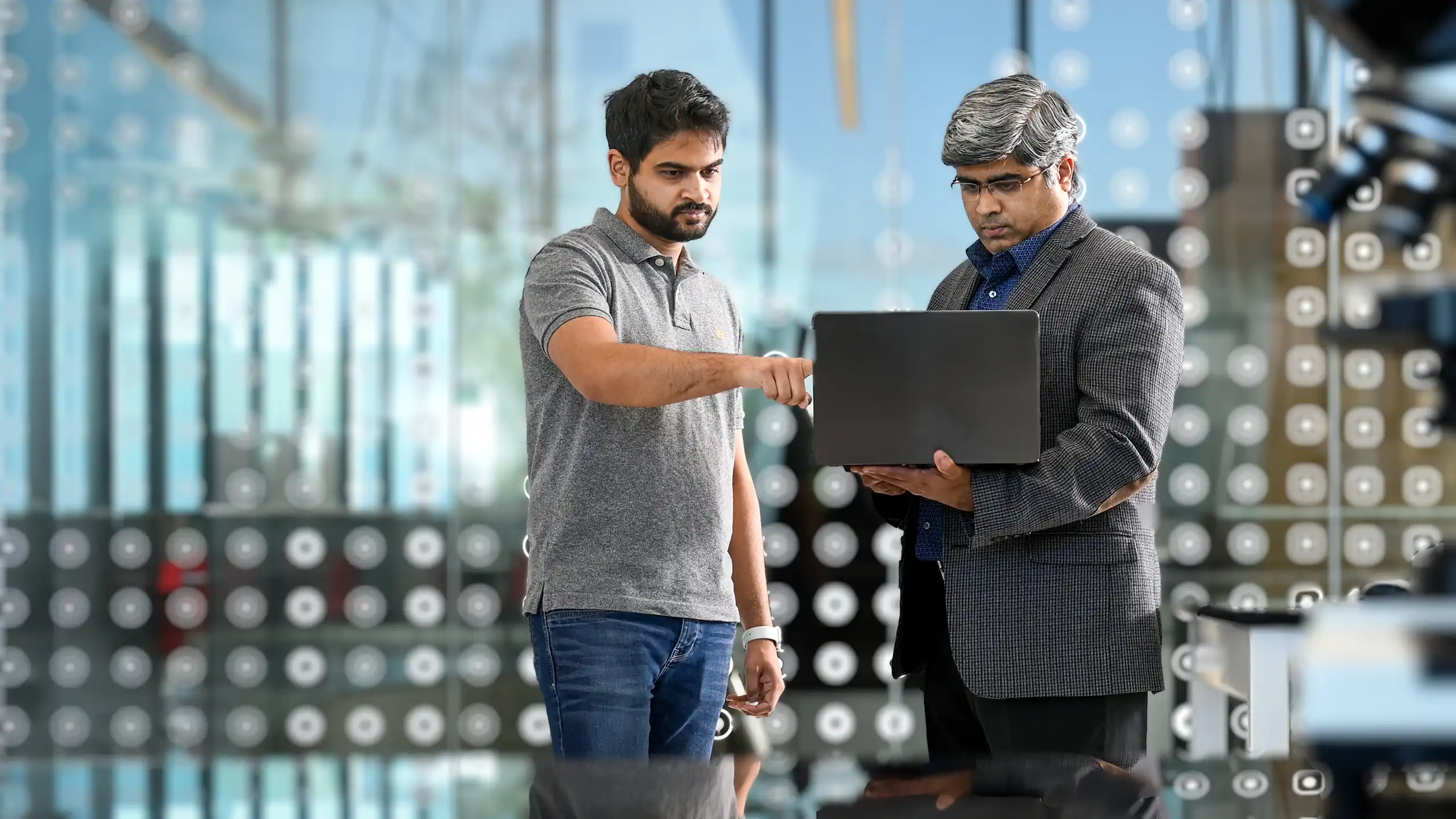 A SPURS student talking with a professor who is holding a laptop about their sustainable proteins research.